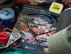 The brochure for Armed Forces Day in Guidlford surrounded by sunglasses and assorted items for a day out.