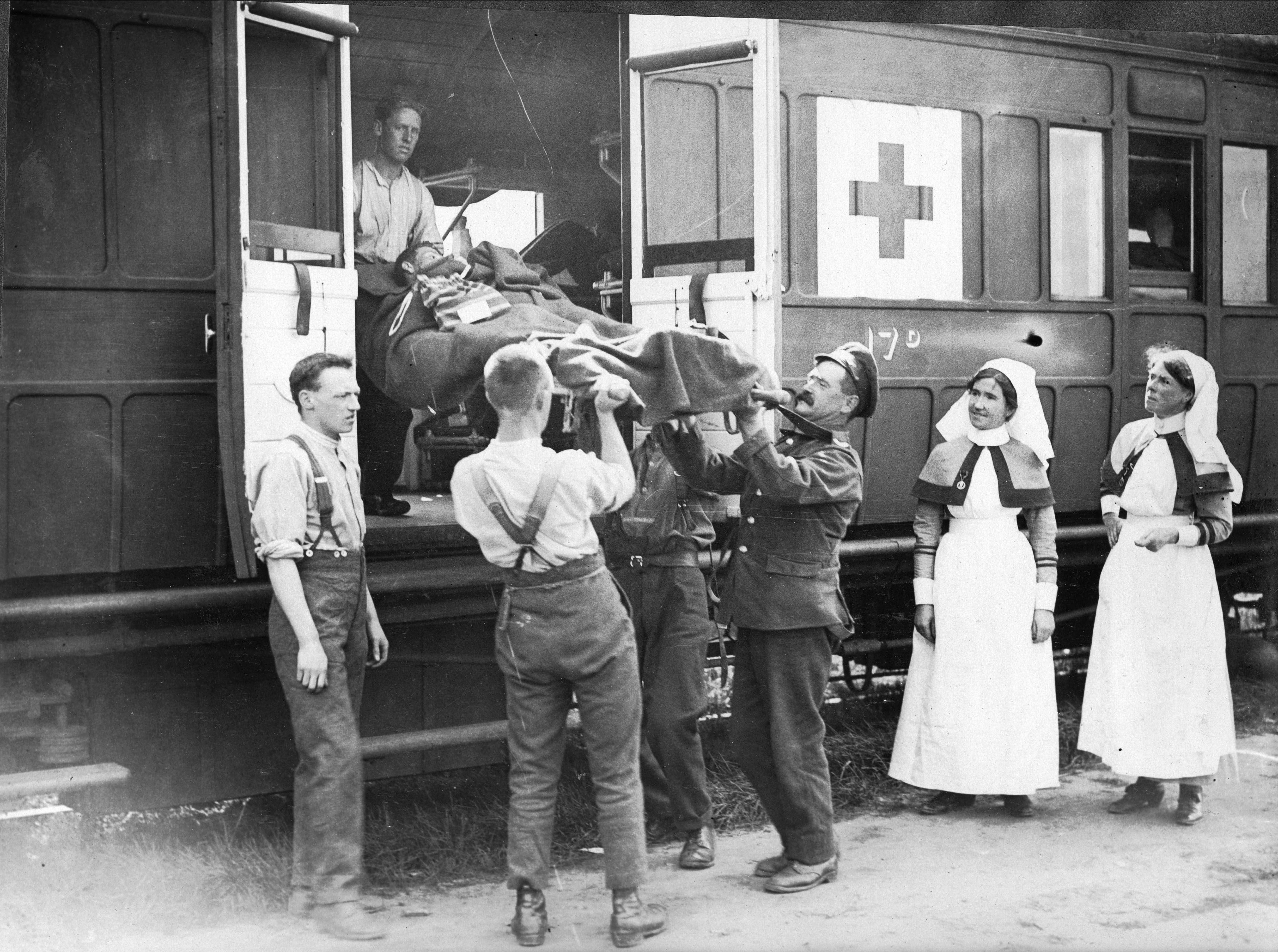 A wounded soldier on a stretcher is loaded on to train 17 by men and women in the friends ambulance unit