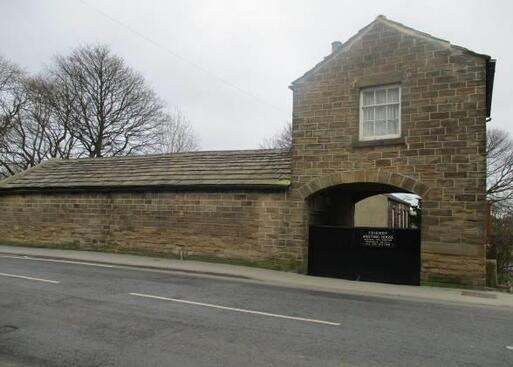 Stone meeting house visible from the street through a large gated archway.