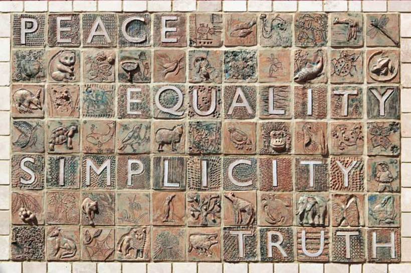 mosaic with the words peace, simplicity, truth, and equality all visible in brown stones. 