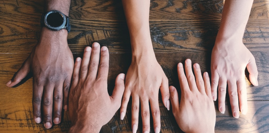 A photograph of a row of hands reaching across a table