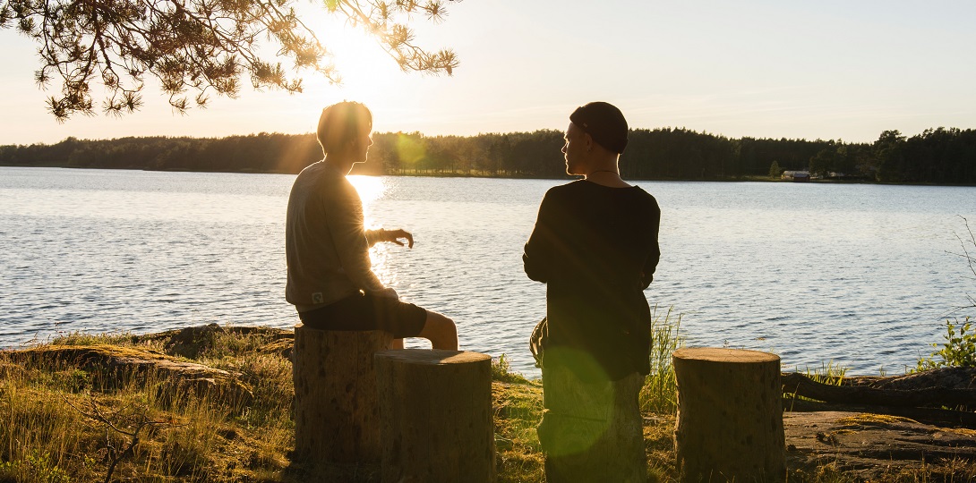 Two men in conversation beside a lake