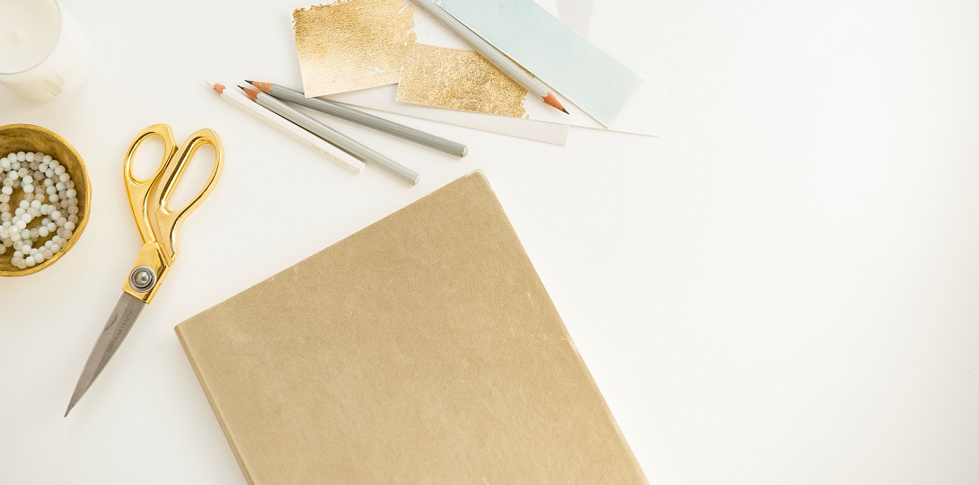 Beige coloured stationery items on a cream coloured surface.