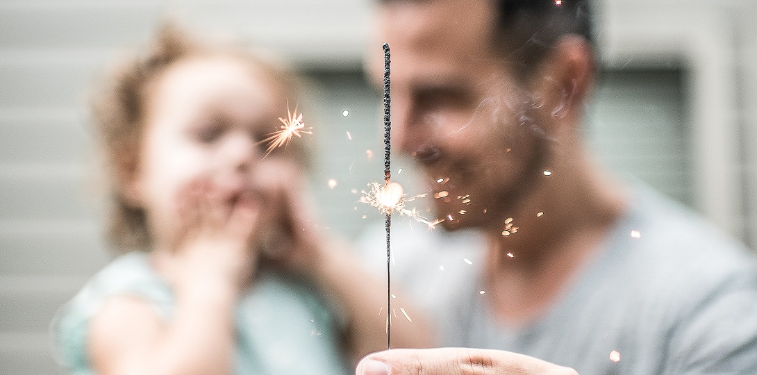 A man holding a young child and a sparkler