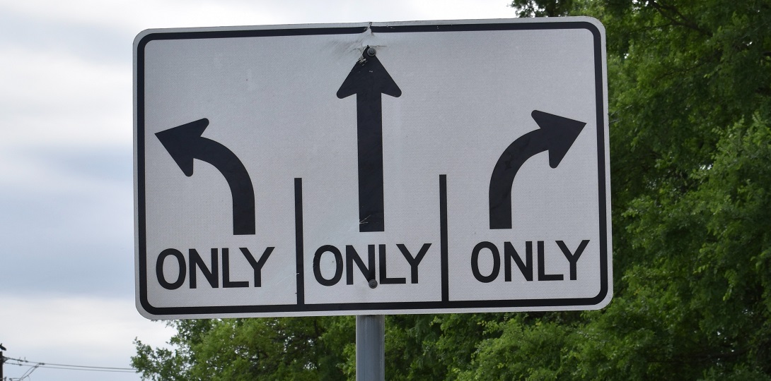 A road sign with arrows pointing in different directions