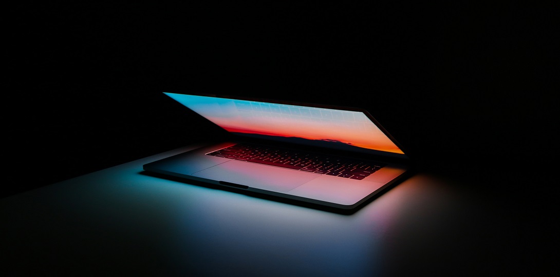 A half open laptop with coloured light coming from the screen
