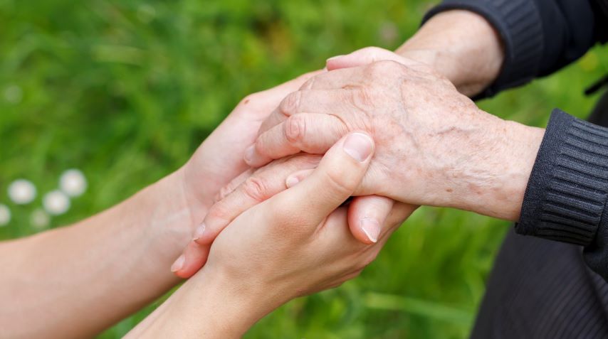 elderly hand being held by a younger hand