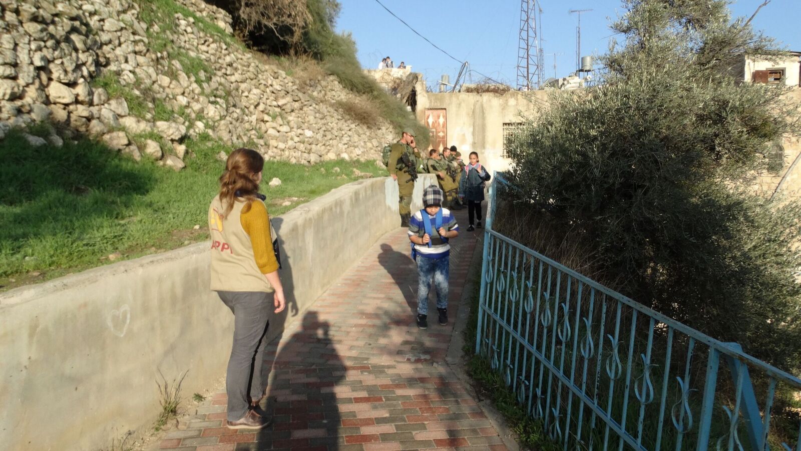 Palestinian schoolchildren encouraged by human rights monitors, pass by Israeli soldiers 