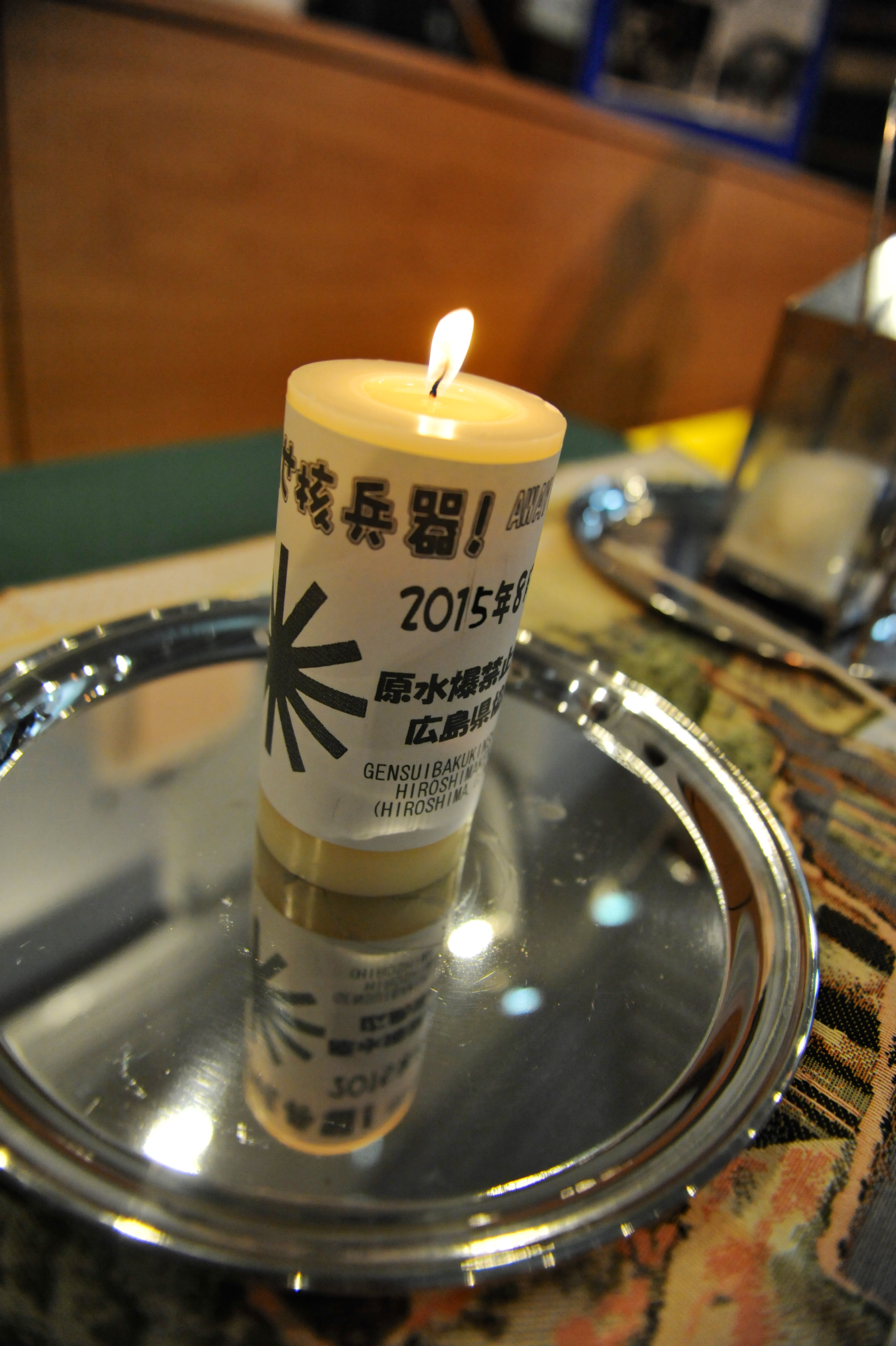 A lit candle on a silver tray. 2015 written in several languages
