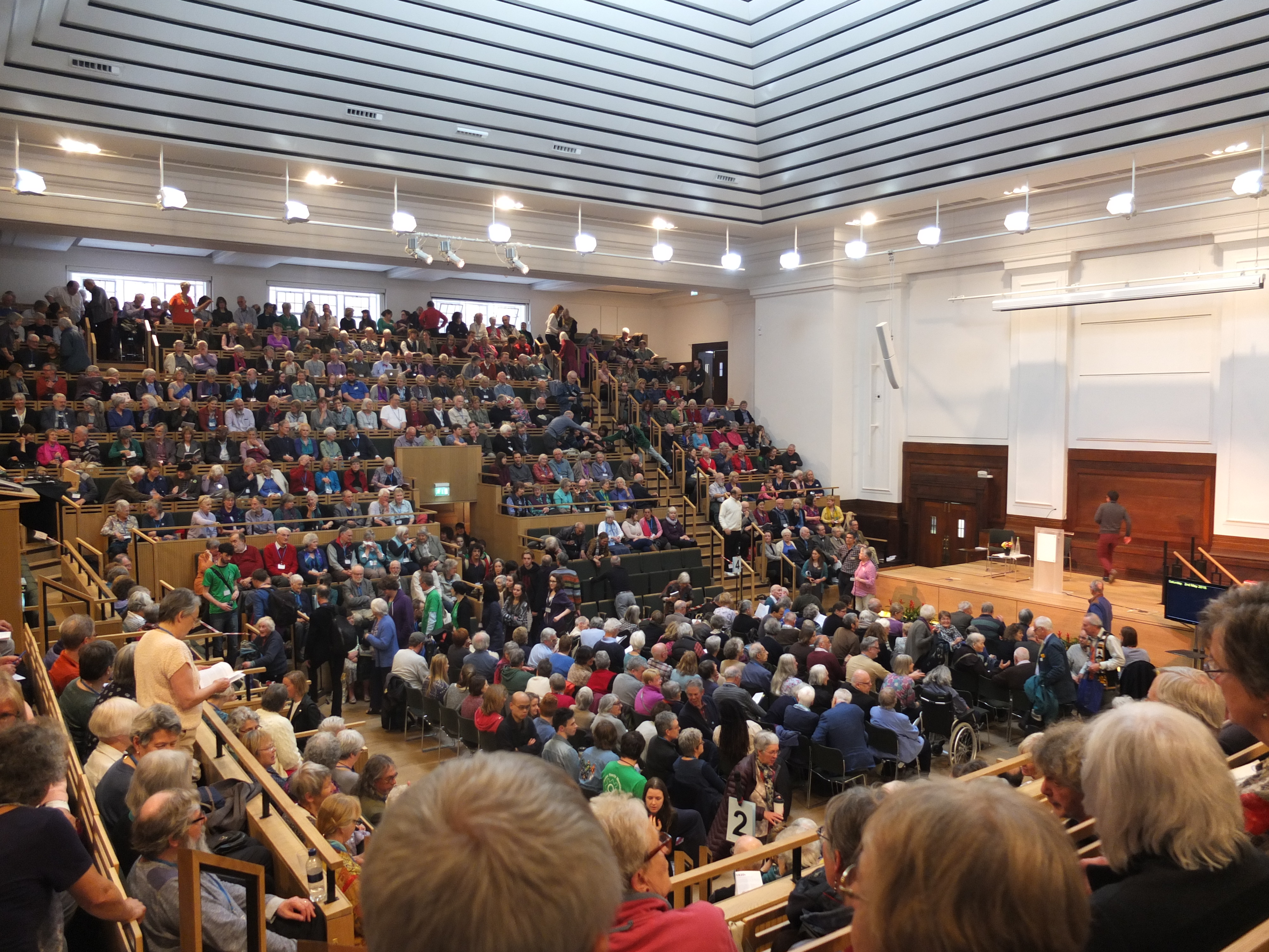 Around 1000 Quakers seated in the tiered large meeting house waiting for the swarthmore lecture to begin