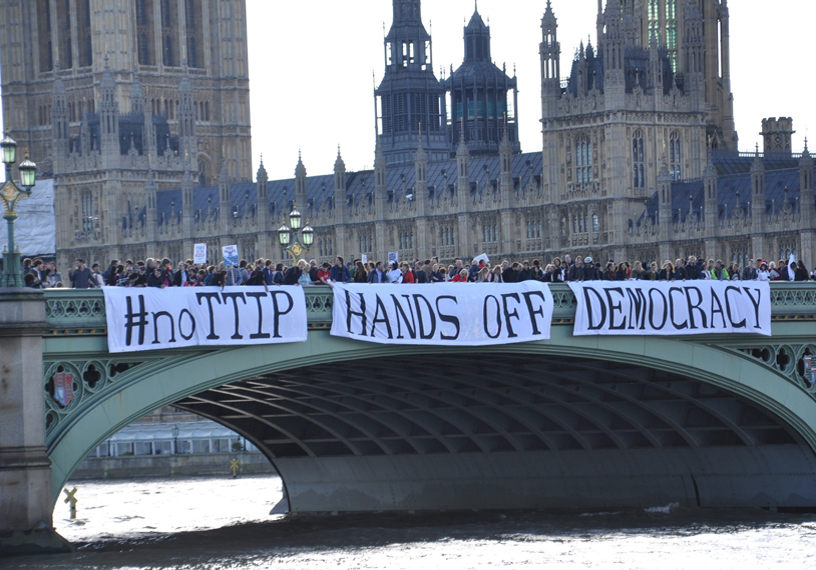 campaigners cross Westminster Bridge where a banner says No to TTiP, hands off democracy