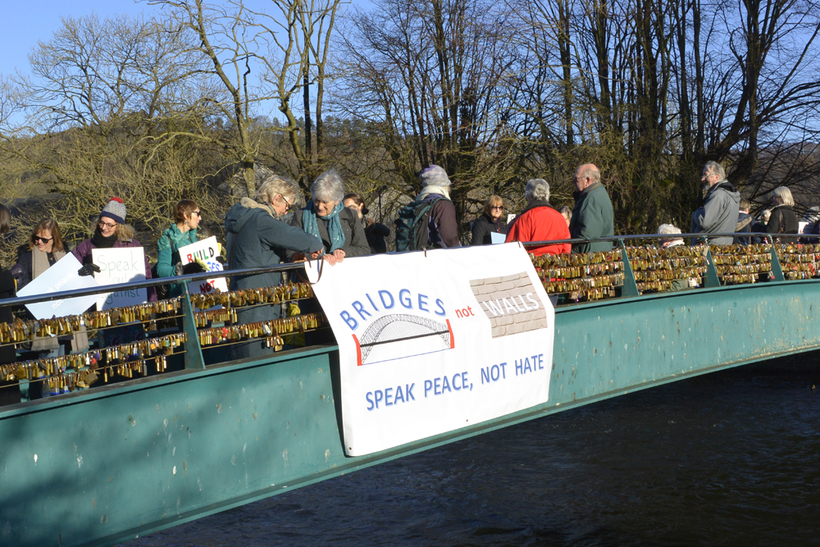 Quakers in Bakewell on a bridge with a banner saying 'bridges not walls'