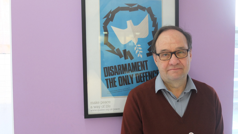 Tim Wallis by a poster which says Disarmament the only defence