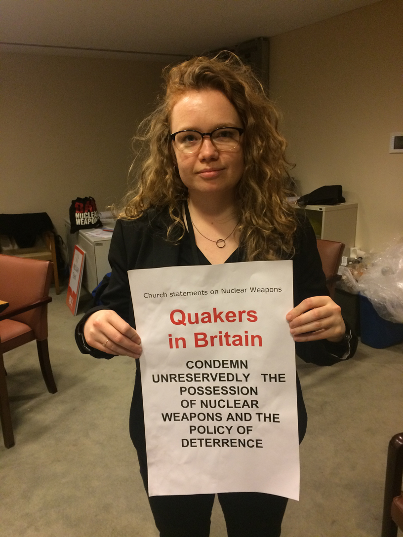 Clare Conboy holds banner setting out Quakers in Britain objection to nuclear weapons