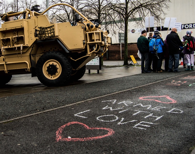 Protesters stand outside the arms expo in Hereford next to their words "Armed with Love" chalked on the floor