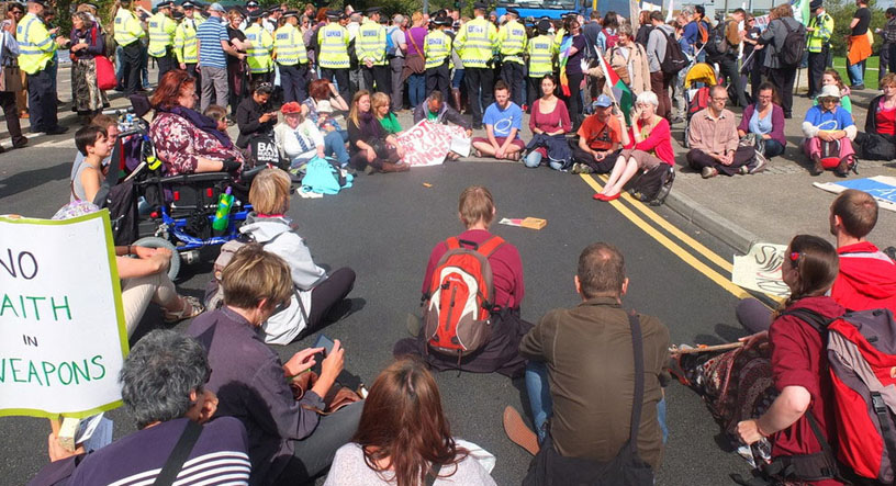 Dozens seated for meeting for worship outside the during the Defence and Security Equipment International (DSEI) arms fair 