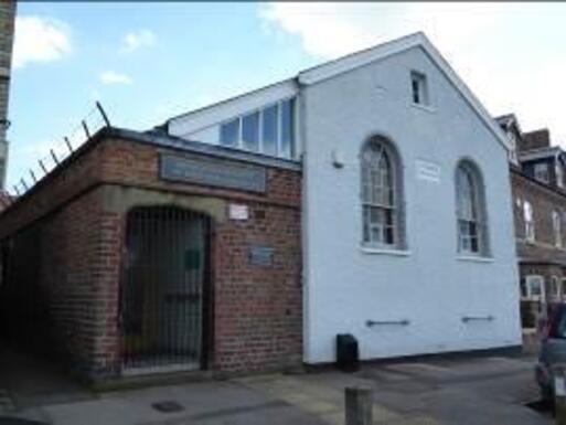 White building with larged arched windows and a side porch. 