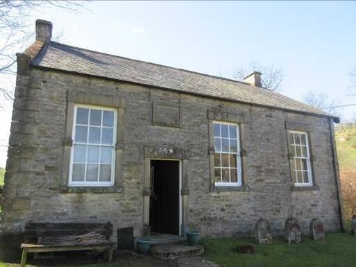 Old stone building with three big windows.