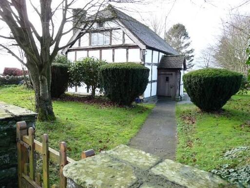 White timber framed house with a garden path leading to its front porch