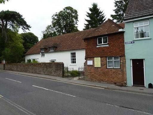 Small terraced brick cottage facing a main road. 