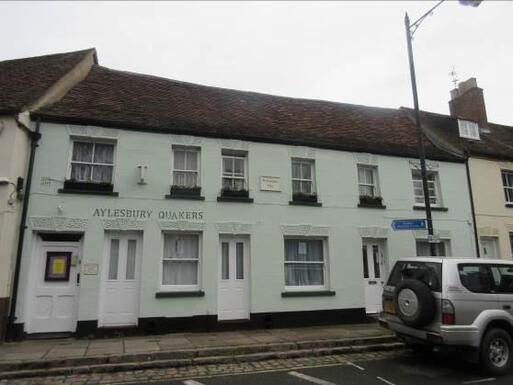 Three white terraced cottages with Aylesbury Quakers painted on its frontage. 