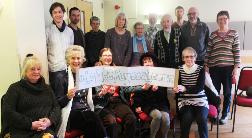 Group of people from Sheffield meeting around a poster saying 'let refugees learn'