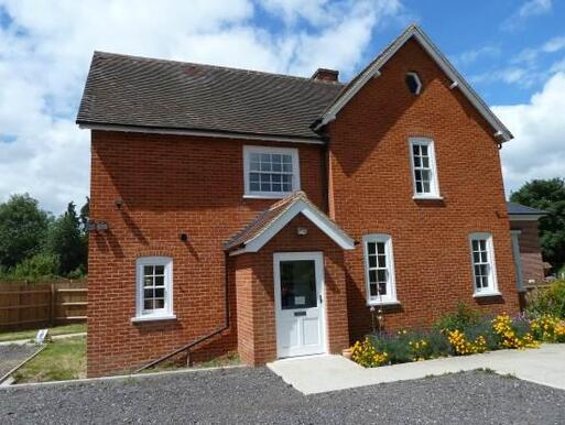 Large redbrick house with a small garden of flowers. 