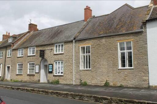 Large stone terraced cottage with Quaker signage and large dual-level windows facing onto the street. 