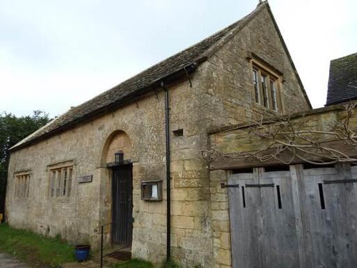 Old stone house with large windows and a lantern above the wooden entrance door. 