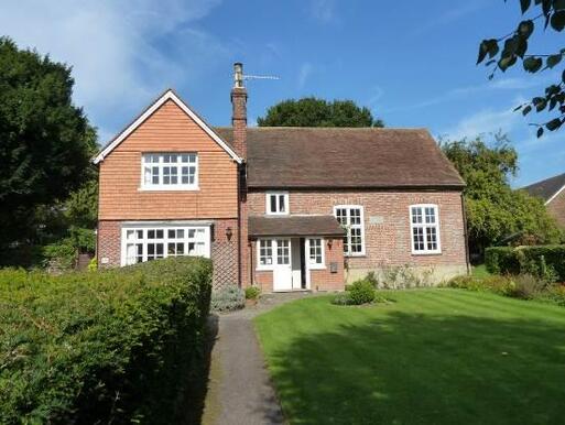 Old brick house with small entrance porch set within large garden grounds.  
