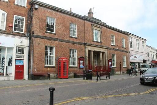 Large brick townhouse with columned entrance, a red telephone box and red noticeboards are immediately to the front of the building.