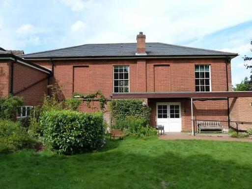 Red brick building within large garden grounds.