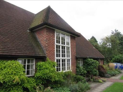 Short brick bungalow with large dual-level window in its central front aspect.