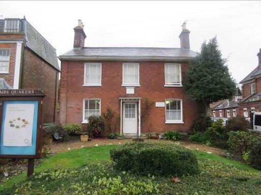 Two-storey red brick house with a wooden noticeboard in the front garden.