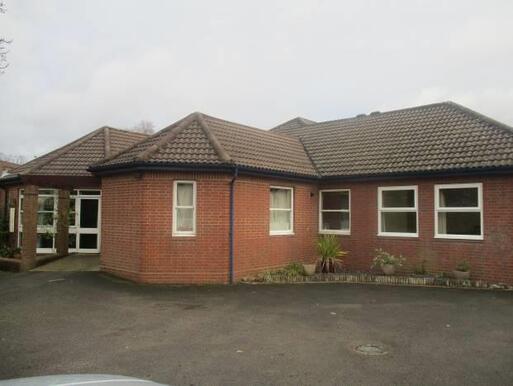 Low brick building with hexagonal feature room extending into the car park.