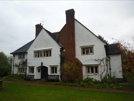 Grand white painted house with large chimney stack and multiple double-span windows, within large gardens.
