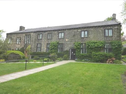 Extensive building  with many windows on each floor with a hedge building.