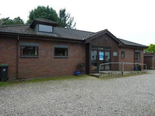 Modern building with big car park and burial ground on the site.