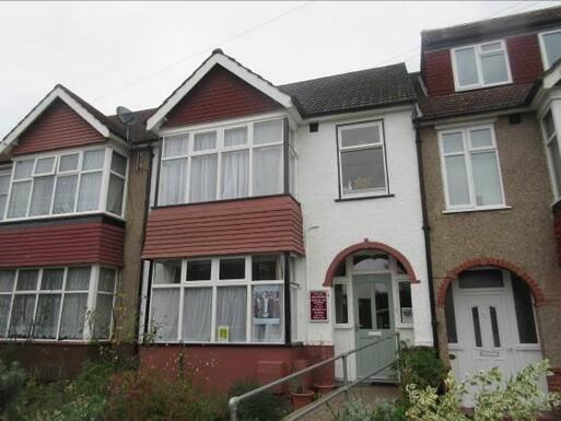 A modest interwar terraced house covered in pebbledashed, with a tile-hung gabled bay.