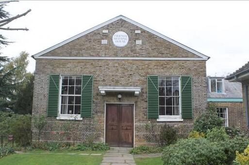 Well-presented meeting house with green shutters and attached burial area.