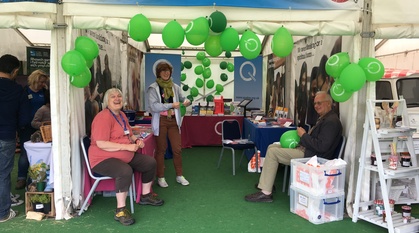 Four people sitting and standing in a tent marked 'Quakers', looking happy