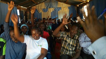 A group of people sitting down with their hands raised