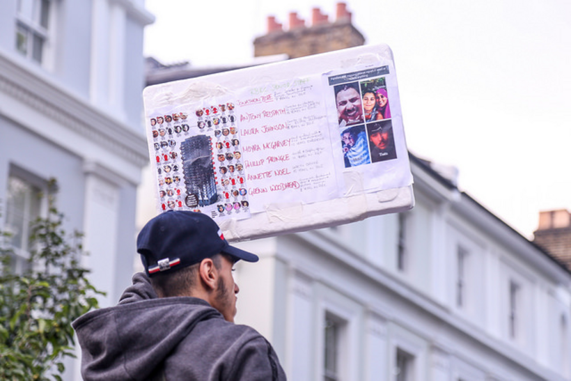 A man holds up the names of those who died in the Grenfell Tower fire. Image: Wasi Daniju/Flickr
