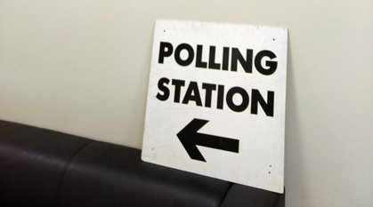 A polling stations sign propped up on the pack of a chair
