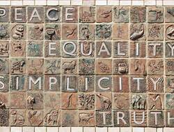 A mosaic in light brown colours includes the words peace, justice, equality and simplicity.