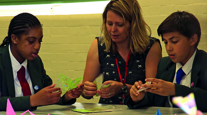 Children and an adult making paper cranes. 