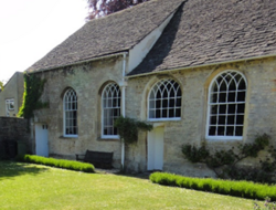 a stone building with large windows photographed from a summer garden.