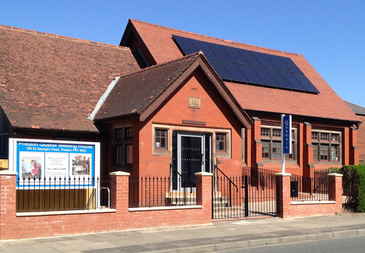 Red brick, single-story building with noticeboard outside.