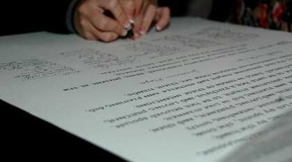 A person signing a Quaker marriage certificate at the end of a long list of signatures.