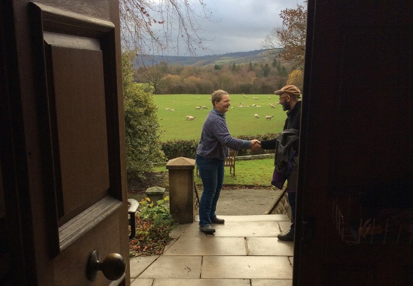 Two people shaking hands in a doorway